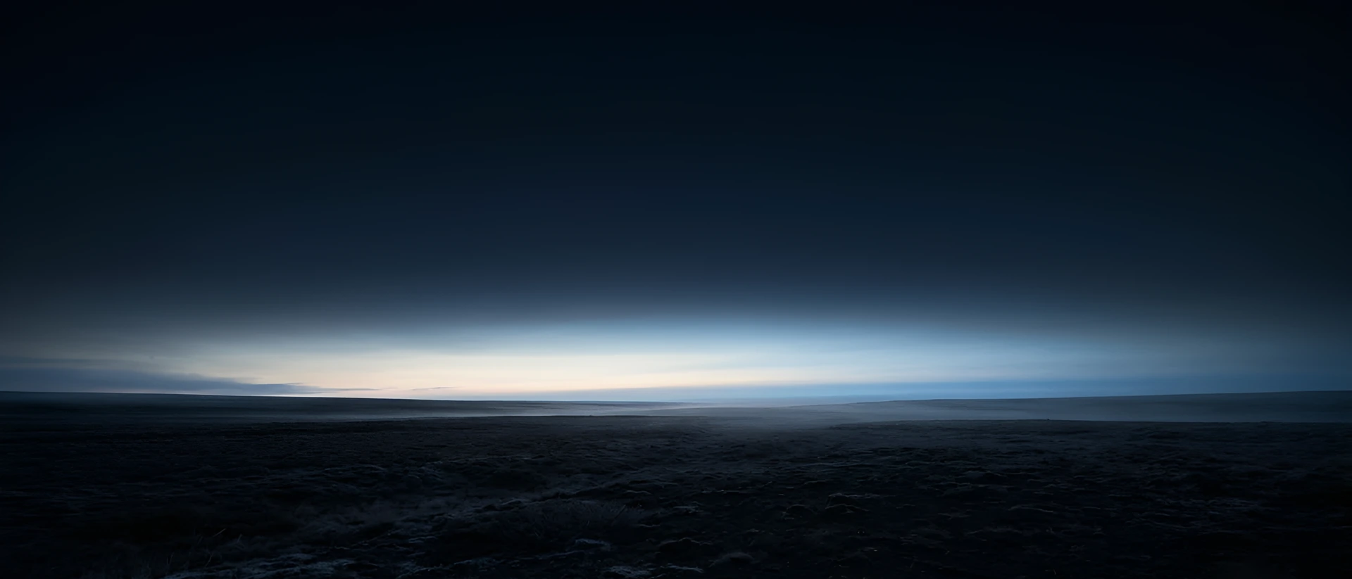 Dawn light spreading along the horizon over a dark plain