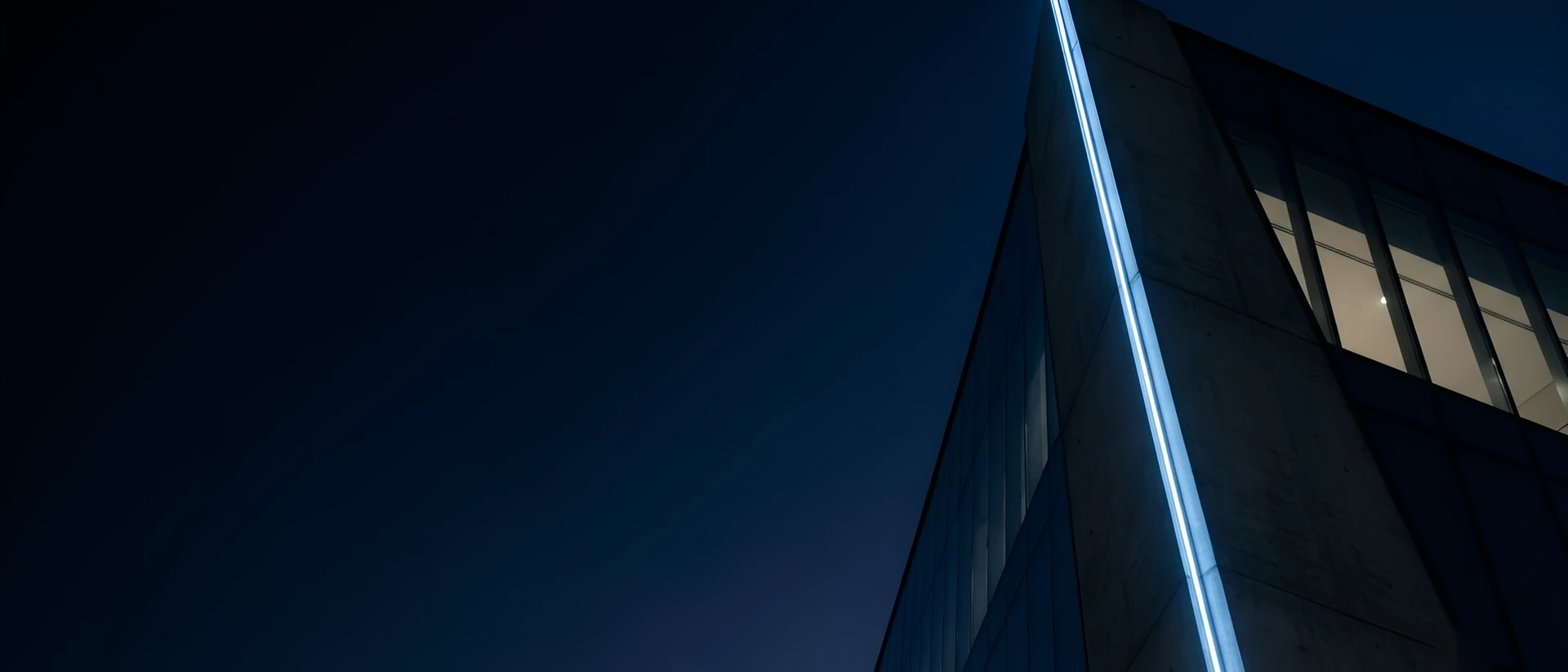 A straight line of light along the edge of a building at blue hour